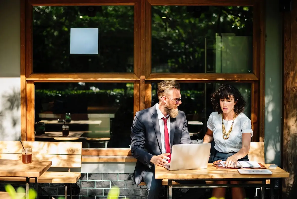 Accountant and client reviewing finances on laptops in a café